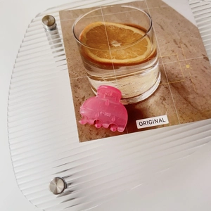 Detail of a matte pink candy-colored hair claw clip on an aesthetic glass tray