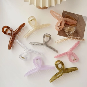Flat lay of colorful acrylic shark hair claws in amber and cream on a clean white background