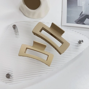 Dettaglio di pinze per capelli opache kaki su vassoio in vetro con design minimalista