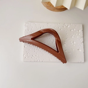 Vue détaillée d'une pince à cheveux triangulaire marron sur socle en pierre