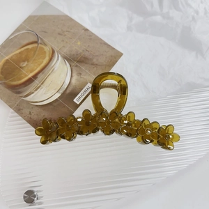 Macro detail of amber flower hair claw clip with translucent resin and metal spring