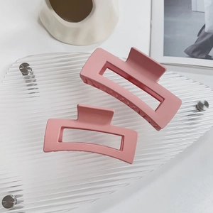 Dettaglio di due grandi mollette rettangolari rosa opaco con design geometrico vuoto