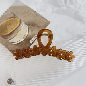 Macro detail of amber floral hair claw clip featuring transparent acrylic flower petals