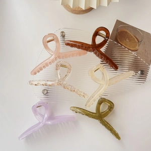 Detailed view of six large hair claws in cream and jelly colors on a glass tray