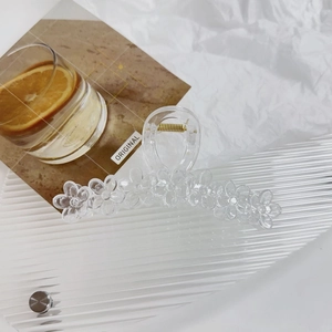 Detail of translucent floral claw clip showing the clear acrylic texture and metal spring