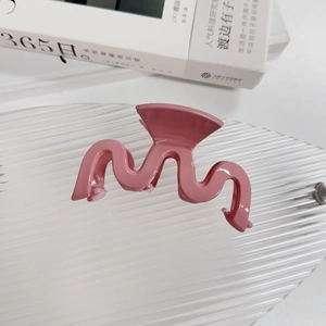 Vue détaillée d'une élégante pince à cheveux rose ondulée sur un plateau décoratif