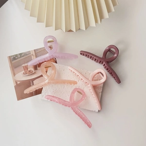 Top view of five colorful oversized resin hair claws displayed on a minimalist white table