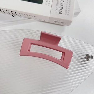 Détail d'une pince à cheveux rose rectangulaire ajourée posée sur un plateau décoré