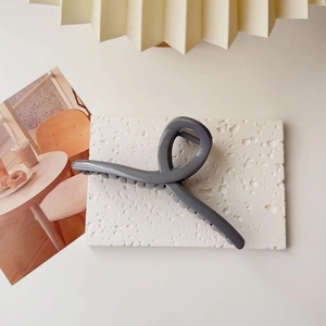 Close-up of matte dark grey oversized hair claw clip on a textured stone display board