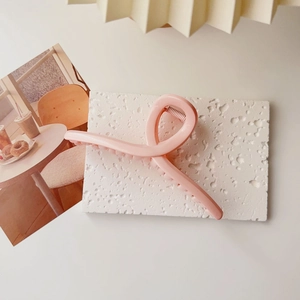Detailed view of large matte pink hair claw clip on a textured stone surface