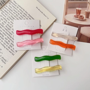 Close-up of six colorful wavy resin hair clips displayed on branded white cards