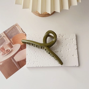 Detailed view of an olive green oversized hair claw clip on a stylish stone surface