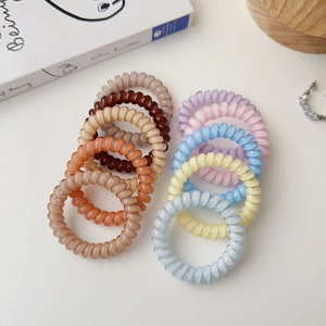 Spiral telephone cord hair ties in assorted matte morandi colors on a clean white surface
