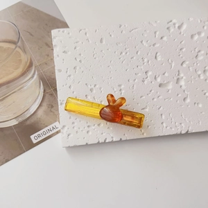 Détail d'une pince à cheveux en résine jaune ambre avec accent orange sur pierre blanche