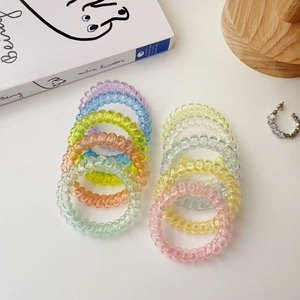 Colorful spiral phone cord hair ties in vibrant candy colors on a clean white desk
