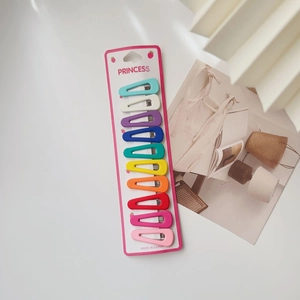 Close-up of ten colorful matte triangle hair clips for kids on a pink paper card