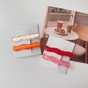 Close-up of translucent colorful wavy hair clips in amber and pink on white card