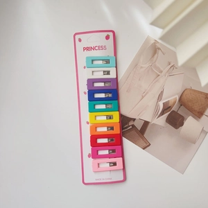 Detailed view of 10 colorful rectangular hair clips arranged on a pink display card