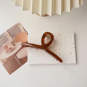 Detailed top view of a large translucent brown claw clip on a white stone tray