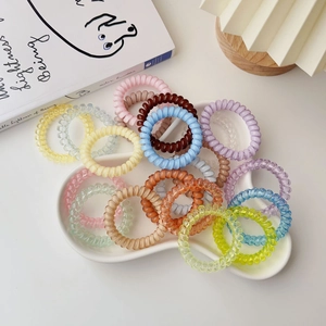 Macro shot of colorful spiral telephone wire hair ties on a cloud-shaped ceramic tray