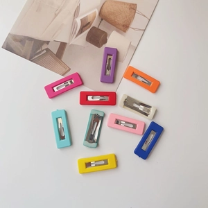 Close-up of 10-piece matte colorful rectangular snap hair clips for kids on white surface