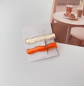 Close-up of wavy acrylic hair clips in transparent champagne and bright orange with glitter