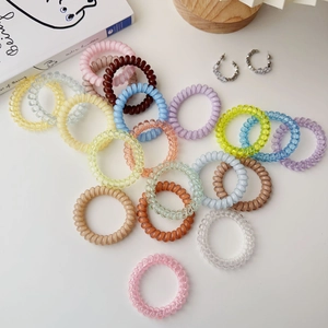 Macro shot of colorful spiral telephone cord hair ties in various pastel shades on a desk