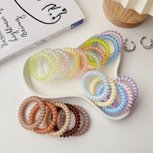 Macro detail of assorted spiral hair coils in candy and Morandi tones on a white plate