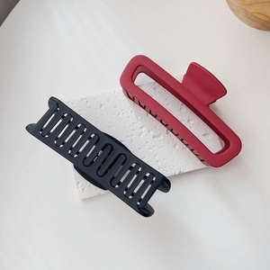 Dettaglio di grandi mollette opache rosse e nere su una superficie di marmo bianco