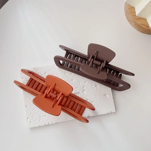 Dettaglio di grandi mollette per capelli opache marrone scuro e caramello con design cavo