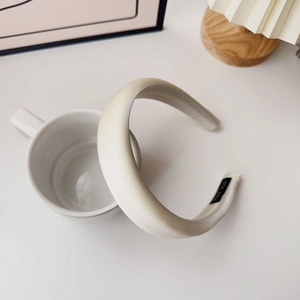 Detail of a beige padded sponge headband on a white cup with a Hand Made label