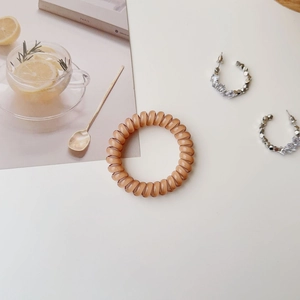 Detail shot of an orange spiral hair tie and sparkling rhinestone hoop earrings on a magazine