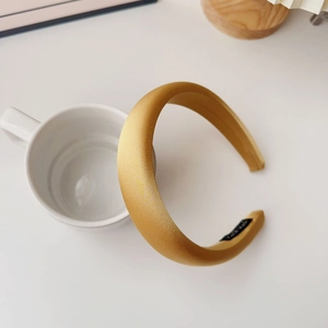 Detail of the golden satin sponge headband texture with soft padding and woven label