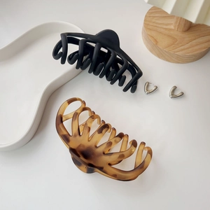 Close-up of large matte black and tortoise shell hair claws on a ceramic plate