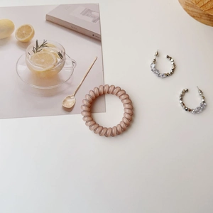 Pink translucent spiral hair tie paired with beaded silver hoop earrings and postcards