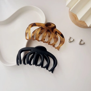 Detail of large amber tortoiseshell and matte black claw clips on a white ceramic plate