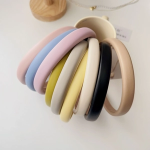 Macro display of thick sponge headbands in multiple pastel colors on a beige cup