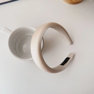 Close-up of handmade label on beige satin padded sponge headband placed on a ceramic cup