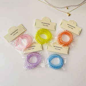 Détail d'élastiques spirales colorés sous emballage transparent avec étiquettes faites main