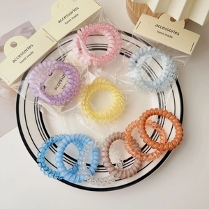 Detail showing colorful spiral hair ties in a ceramic bowl with transparent packaging