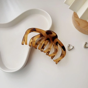 Detail shot of large amber tortoise shell hair claw clip on a white ceramic plate