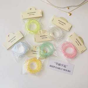 Détail d'élastiques à cheveux spirales colorés dans un emballage transparent