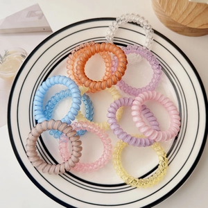 Macro shot of colorful spiral telephone cord hair ties on a white ceramic plate