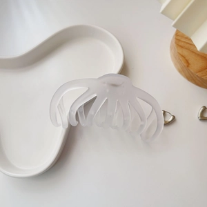 Detail shot of a matte white octopus hair claw clip on an elegant ceramic tray