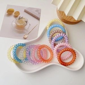 Close-up of a colorful spiral hair tie set in a decorative white ceramic tray