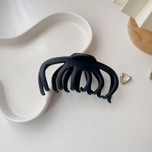 Detailed view of matte black octopus hair claw clip on a minimalist ceramic plate