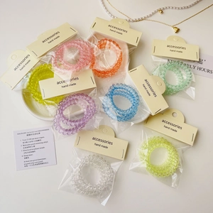 Détail de sept élastiques spirales colorés en emballages individuels avec cartes crème