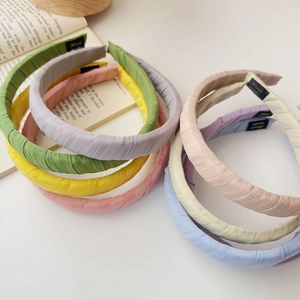 Detail of fabric headbands with pleated texture and handmade labels on white desk