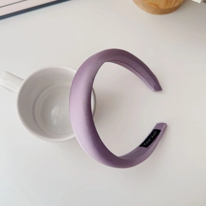 Detail of purple padded satin headband with Hand Made label on a ceramic cup