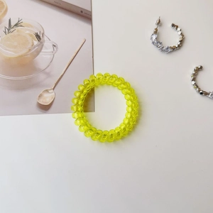 Macro shot of a yellow spiral telephone cord hair tie with a translucent resin texture